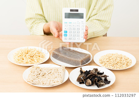 Middle-aged woman with food containing a lot of dietary fiber and a calculator Middle-aged woman with food containing a lot of dietary fiber and a calculator 112033297
