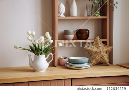Stylish interior of a wooden Scandinavian kitchen. Fresh flowers in a vase. 112034259