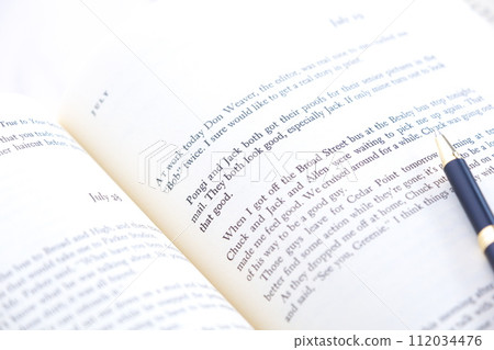 一個人放鬆並享受打開書頁閱讀英文書的圖片。 112034476