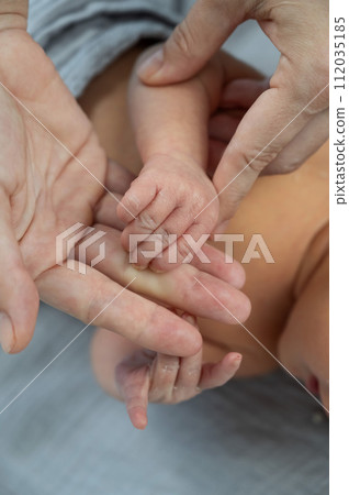 A newborn boy holds his mother's finger. Close-up of hands. 112035185
