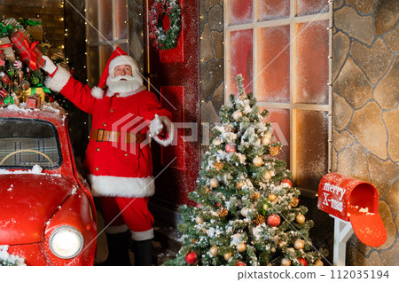 Santa Claus loads gifts on a red retro car. Merry Christmas.  112035194