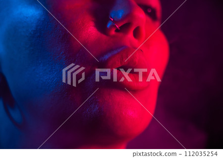 Asian woman with short haircut smoking in neon light. close-up portrait. Asian woman with short haircut smoking in neon light. close-up portrait. 112035254