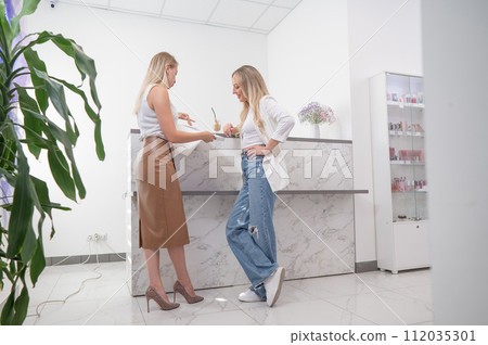 Eyelash extension master shows examples to a client. Woman choosing type of eyelash extension.  112035301