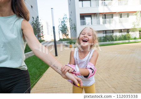 Mother helps daughter learn to roller skate.  112035338