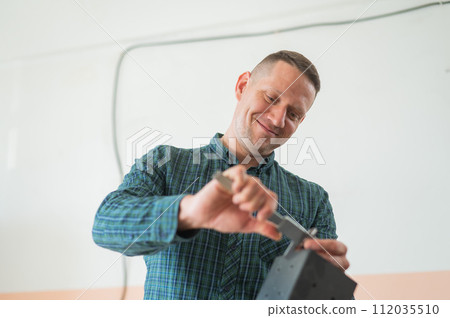 Carpenter measures a metal connector for wooden parts. Carpenter measures a metal connector for wooden parts. 112035510