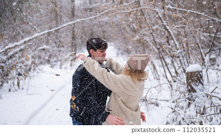 A young couple walks in the park in winter. Guy and girl hugging outdoors. A young couple walks in the park in winter. Guy and girl hugging outdoors. 112035521