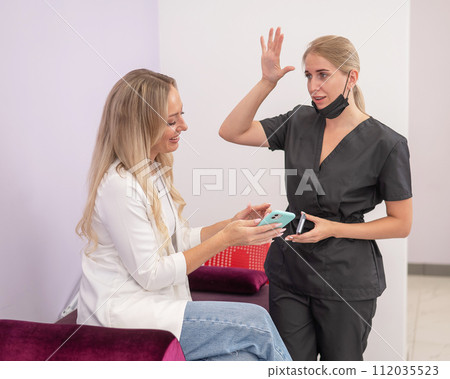 A woman shows the desired result to the master on a smartphone. A woman shows the desired result to the master on a smartphone. 112035523
