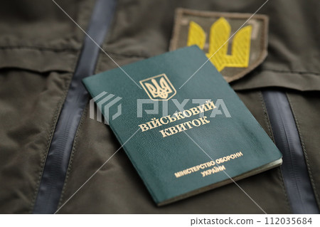 Military token or army ID ticket lies on green ukrainian military uniform indoors close up Military token or army ID ticket lies on green ukrainian military uniform indoors close up 112035684