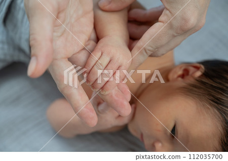 A newborn boy holds his mother's finger. Close-up of hands. 112035700