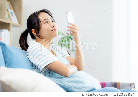 年輕女子在客廳看智慧型手機 112035854