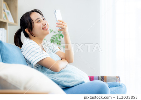 年輕女子在客廳看智慧型手機 112035855