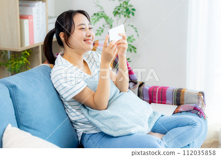 Young woman looking at her smartphone in the living room Young woman looking at her smartphone in the living room 112035858