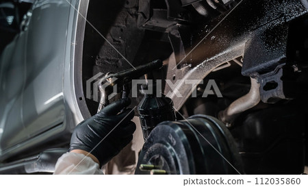 The master sprays an anti-corrosion compound on the bottom of the car. The master sprays an anti-corrosion compound on the bottom of the car. 112035860