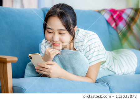 年輕女子在客廳看智慧型手機 112035878