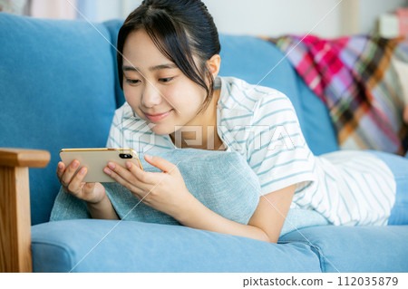 年輕女子在客廳看智慧型手機 112035879
