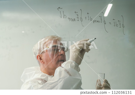 An elderly Caucasian male chemist in a protective suit writes on glass.  112036131