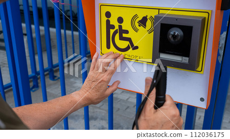 Close-up of the hands of a blind elderly woman reading a text in braille. Button for calling help for people with disabilities. Close-up of the hands of a blind elderly woman reading a text in braille. Button for calling help for people with disabilities. 112036175