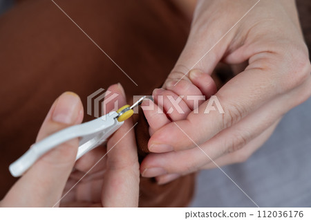 Mom cuts her newborn son's fingernails with small children's scissors. Mom cuts her newborn son's fingernails with small children's scissors. 112036176