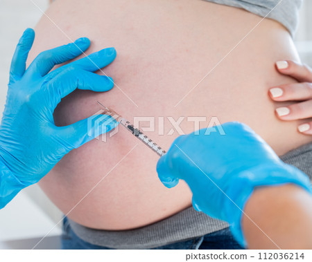 Doctor gives an injection in the stomach of a pregnant woman.  112036214