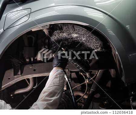 The master sprays an anti-corrosion compound on the bottom of the car. 112036418