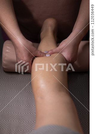 Close-up of a woman's leg massage in a salon. Vertical photo. Close-up of a woman's leg massage in a salon. Vertical photo. 112036449