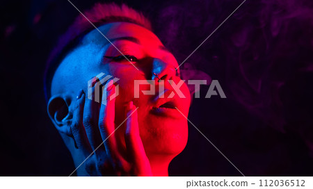 Asian woman with short haircut smoking in neon light. close-up portrait. Asian woman with short haircut smoking in neon light. close-up portrait. 112036512