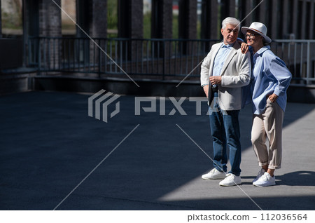 Stylish mature couple. Gray-haired man and woman holding hands while walking around the city.  112036564