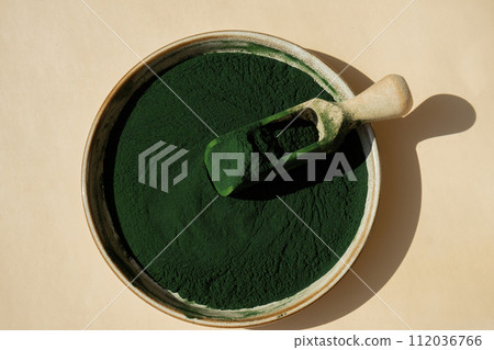 Natural organic green spirulina algae powder in bowl and wooden spoon on neutral background. Chlorella seaweed vegan superfood supplement source and detox. Copy space Healthy nutritional antioxidant Natural organic green spirulina algae powder in bowl and wooden spoon on neutral background. Chlorella seaweed vegan superfood supplement source and detox. Copy space Healthy nutritional antioxidant 112036766