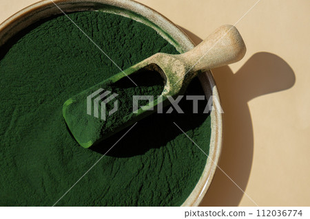 Organic blue-green algae spirulina powder food in plate with wooden spoon. Copy space for your text Health benefits of spirulina chlorella. Vitamins and minerals to diet. Detox dietary supplement 112036774