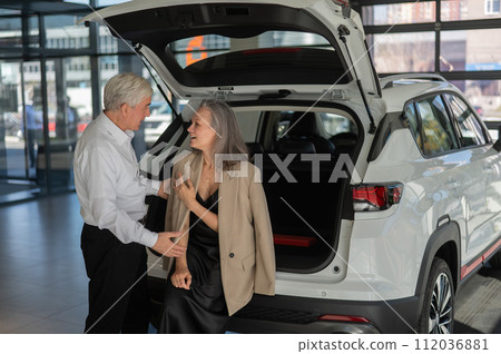 Mature Caucasian couple choosing a car looks at the trunk. Mature Caucasian couple choosing a car looks at the trunk. 112036881