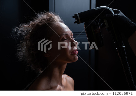 A master applies tinting paint to the face of a Caucasian woman. Instant tanning procedure 112036971