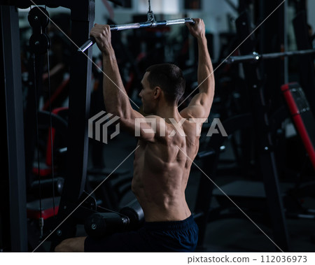A man does a chest pulldown in the gym. A man does a chest pulldown in the gym. 112036973