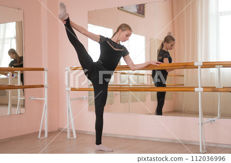Caucasian blonde woman is practicing ballet in class. Ballerina rehearsing at the barre.  112036996