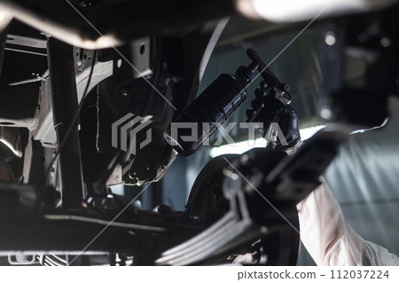 The master sprays an anti-corrosion compound on the bottom of the car.  112037224