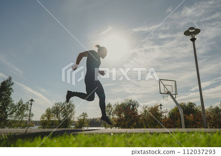 Caucasian man jumping with high hip raise outdoors. Caucasian man jumping with high hip raise outdoors. 112037293
