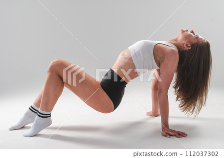 Athletic Caucasian woman in shorts and crop top posing on white background.  112037302
