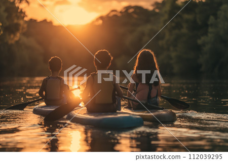 Children sitting on paddleboard in front of parents at weekend 112039295