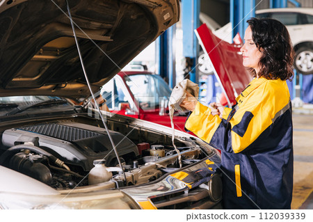 Garage auto mechanic women worker working check engine oil level stick in car service center professional working Garage auto mechanic women worker working check engine oil level stick in car service center professional working 112039339
