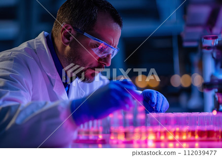 Biotech Research- Scientist viewing samples in multi well plate ready for analysis during a experiment in the laboratory 112039477