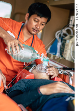 Paramedics Emergency EMS team using Reusable Manual Resuscitator or Ambu Bag to help accident patient breathing in hospital car mobile unit 112039983