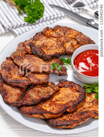 fried juicy pork steaks with ketchup on plate fried juicy pork steaks with ketchup on plate 112040340
