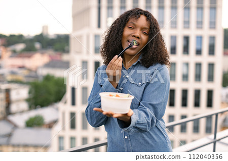 Hungry African American woman holding a bowl of fresh salad 112040356