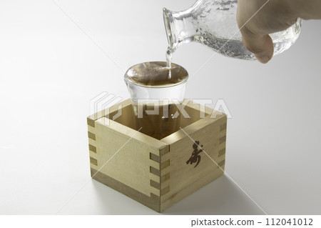 Clear sake poured from a glass bottle Clear sake poured from a glass bottle 112041012