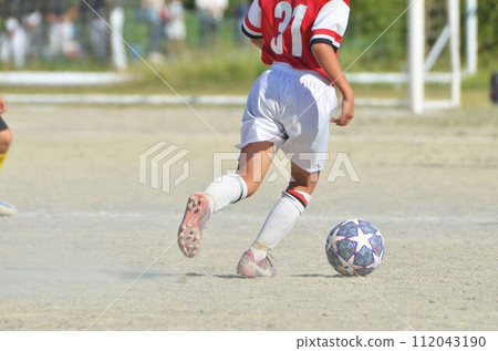 Youth soccer match (player dribbling) 112043190