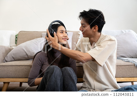 Happy couple asian young women happy playing with headphones while spending time together couch in living room at home 112043811