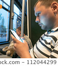 AI-generated content. A man with a cat and smartphone in public transport. High quality photo 112044299