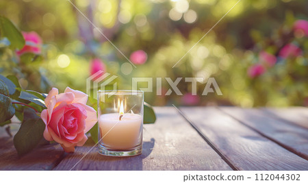 AI-generated content. A candle and rose on a wooden table, with a lush garden backdrop. 112044302