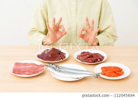 A middle-aged woman makes a circle sign with food containing a lot of B vitamins. A middle-aged woman makes a circle sign with food containing a lot of B vitamins. 112045694