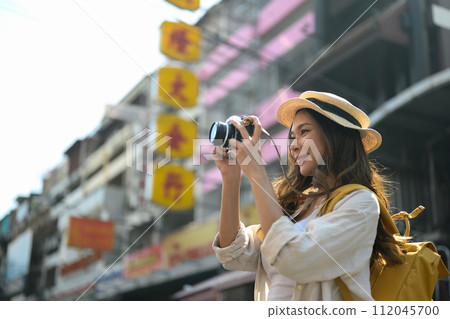 Young female traveller photographing local city street scene with camera Young female traveller photographing local city street scene with camera 112045700