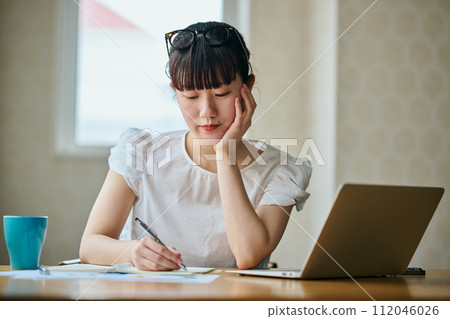 一位年輕女子靠著下巴在筆記本上記筆記 112046026